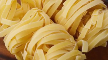 Fettuccine makarnası ahşap masada dönüyor. Makarna malzemelerinin üzerine bak