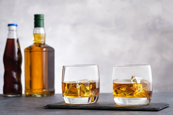 グラスとウイスキーとアイスキューブを背景に2つのボトル — ストック写真