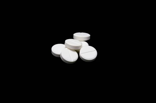 Белые таблетки, изолированные на черном — стоковое фото