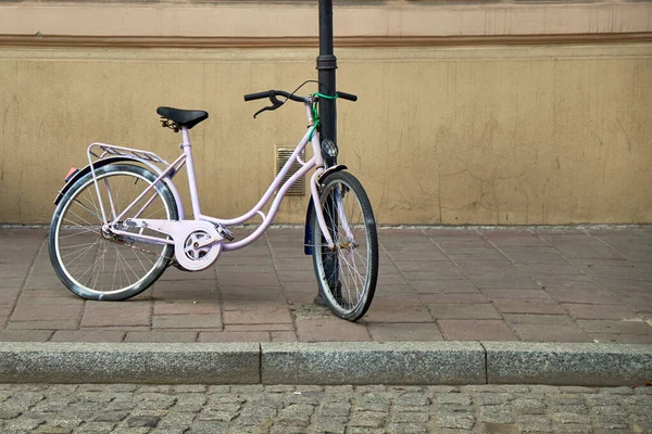 Bicicleta rosa aparcada cerca del poste de la lámpara. Derecho comunitario, libre circulación de mercancías, libre circulación de mercancías, libre circulación de mercancías — Foto de Stock