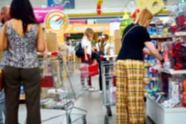 Işığın ve modern süpermarketin içinde yürüyen insanların odaksız fotoğrafı. Arkaplan olarak reklam, sunum ve hareket tasarımı için kullanılabilir