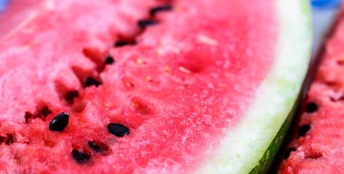 Büyütülmüş makro shot ile kırmızı dilimlenmiş karpuz ve ahşap masaya yakın çekim. Arkaplan