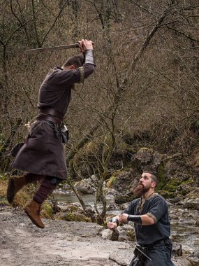 Rive kıyısında kılıçla iki Viking savaşçıları mücadele