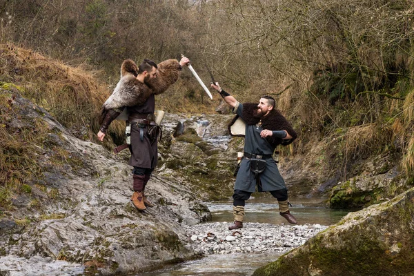 バイキングの 2 つの戦士の川の銀行に剣で決闘します。 — ストック写真