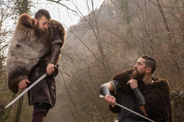 Dos guerreros vikingos luchan con la espada en el bosque — Foto de Stock