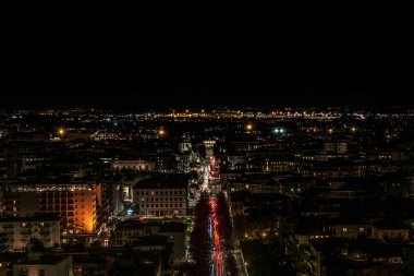 Aydınlanmış şehrin gece manzarası, araba ışıklarının izleri kesilmiş.