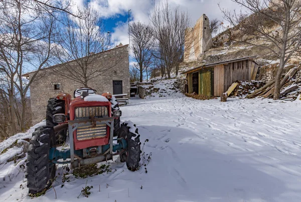 古いトラクターの田舎の山のシーンは雪の中庭に駐車 — ストック写真