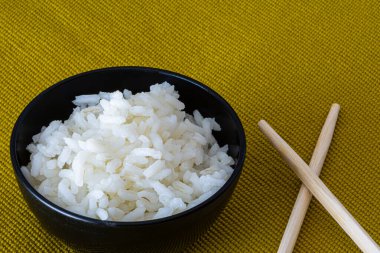 Hafif arka planda Çin yemek çubukları olan pirinç kasesi.