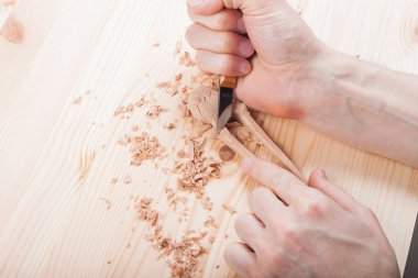 Usta, geleneksel zanaatkar ahşaptan aksesuarlar yontuyor.