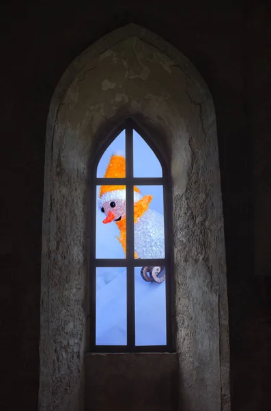 Χιονάνθρωπος σχετικά με το έλκηθρο μέσα από ένα παράθυρο στο κάστρο — Φωτογραφία Αρχείου