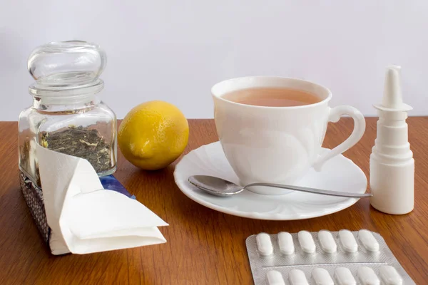 A cup of tea with medicines and a handkerchief