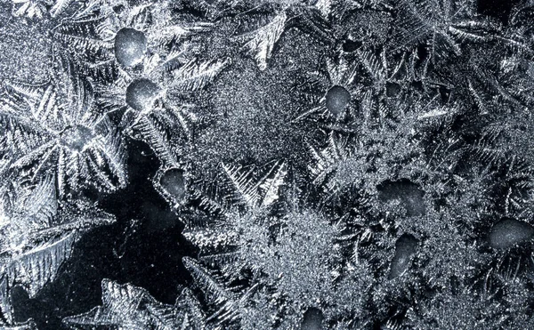 Ornamentos em uma janela congelada em um fundo preto — Fotografia de Stock