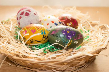 Hasır sepet içinde renkli Paskalya yumurtaları vardır
