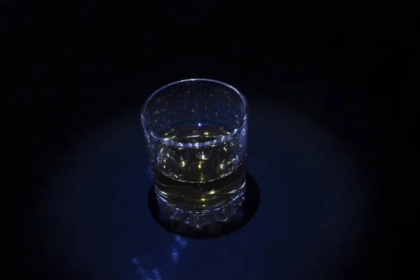 Glass with whisky on black background blue light — Stock Photo, Image