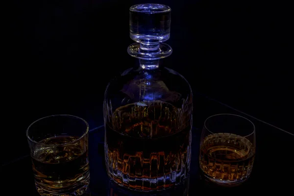 Decanter glass whisky black background blue light — Stock Photo, Image