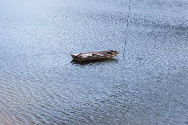 Barajın ortasında küçük bir tekne. Güneşin altında su parlıyor.