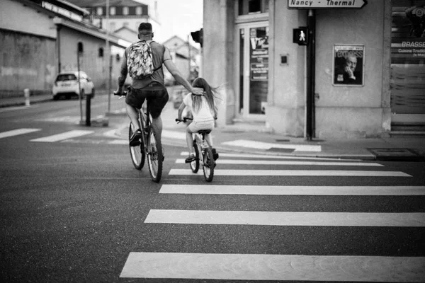 Hombre cruzando la carretera con su hija en bicicletas — Foto de Stock