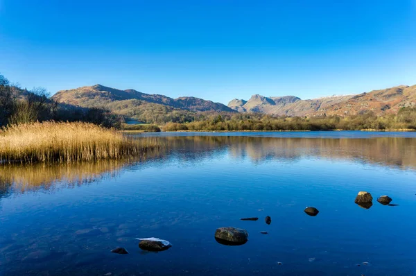 Um Elterwater calmo com os Langdale Pikes à distância — Fotografia de Stock