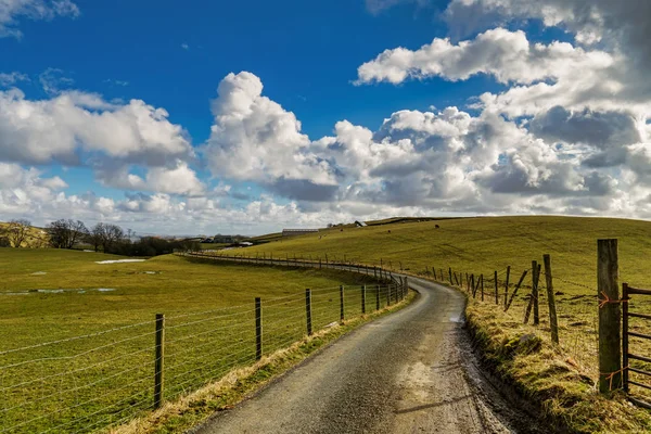 Una strada di campagna inglese che conduce attraverso terreni agricoli . — Foto Stock