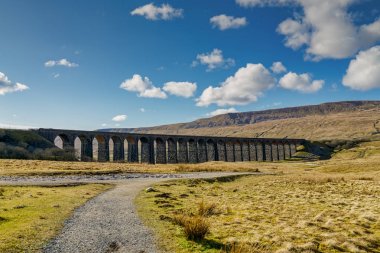 A distant view of the Ribblehead viaduct, on a sunny day clipart