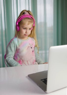 Bilgi işlem eğitimi, ilkokul, öğrenme, dizüstü bilgisayar kullanan kulaklıklı 5 yaşında bir çocuk. kız bilgisayarda oynuyor