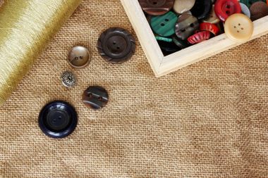 buttons and spool of thread on burlap