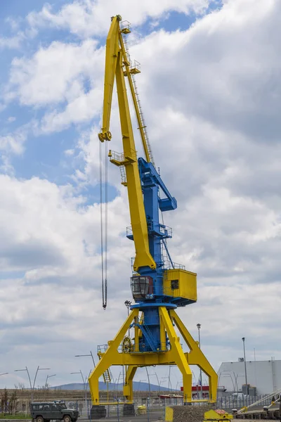 Ein hoher Hafenkran in blau und gelb vor dem Hintergrund eines dramatischen Himmels — Stockfoto