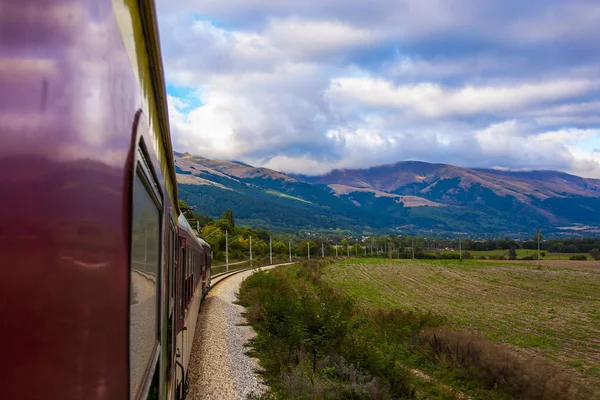 bir dağ manzarası, güzel bir gökyüzü beyaz bulutlar ve yeşil çimen, hareket halinde bir tren tarafından fotoğraflandı. bir tren yolculuğu, romantik bir tren yolculuğu