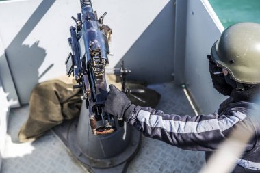 bir denizci bir sigara içiyor ve bir savaş gemisi ise bir makinalı tüfek tutar. Deniz Kuvvetleri Deniz asker korunan ve silahlarla donanmış güverteden izledim.