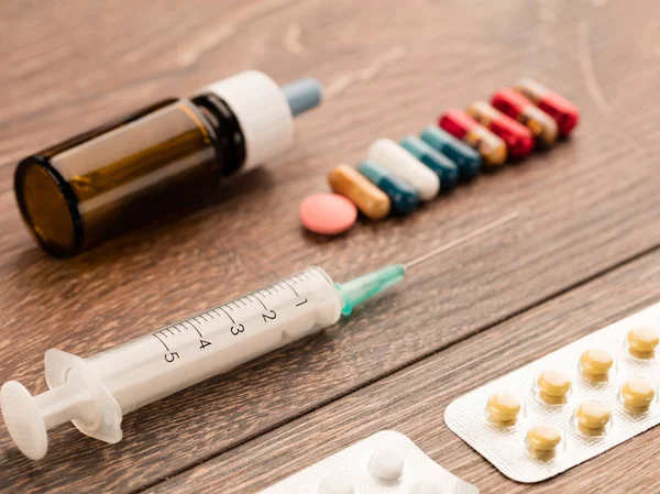 Spritze und Kapsel, medizinische Ampulle und Tabletten auf einem Holztisch. — Stockfoto