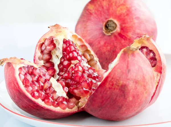 Fruta de granada madura en una placa de porcelana blanca — Foto de Stock