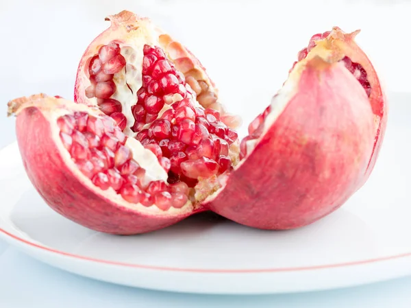 Fruta de granada madura en una placa de porcelana blanca — Foto de Stock