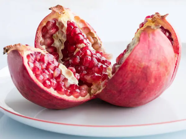 Fruta de granada madura en una placa de porcelana blanca — Foto de Stock