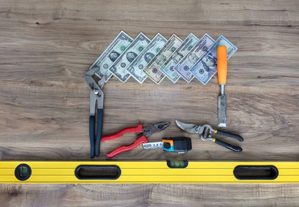 Old construction tools and a set of dollar bills on a wooden table close-up