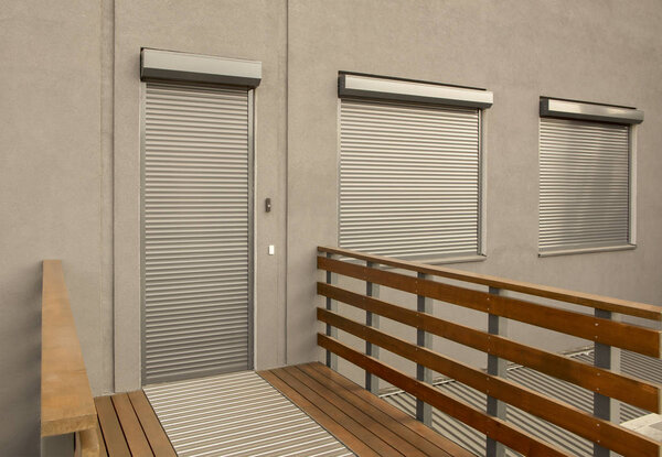 Metal blinds on the doors and windows of the facade of the house