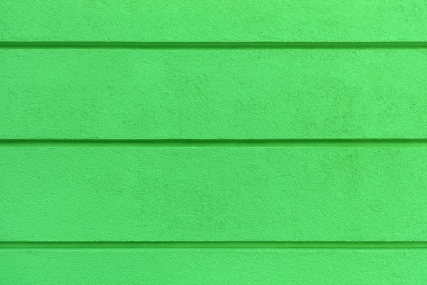 Concrete wall texture with colored bright greenlaster. Construction coat-plaster made of insulated material on the wall with horizontal dividing grooves.