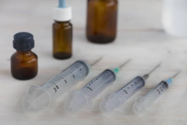 Seringues et ampoules médicales sur une table en bois blanc . — Photo