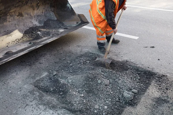 Reparación parcial de la carretera asfaltada. El trabajador limpia una mala parte de la carretera — Foto de Stock