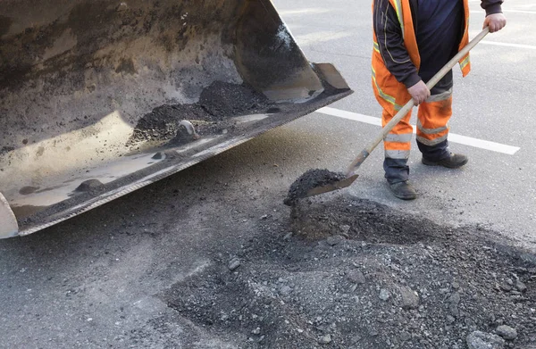 Reparación parcial de la carretera asfaltada. El trabajador limpia una mala parte de la carretera — Foto de Stock