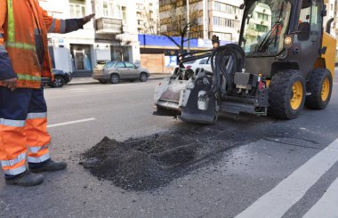 Traktör asfalt üzerinde hasar tamiri için bir meme ile.