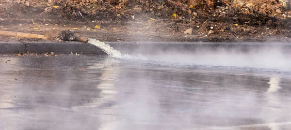 Breakthrough pipes with hot water, water is pumped out onto the road with a pump and a fire hose, close-up. — Stock Photo, Image