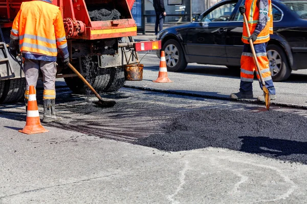 El grupo de trabajadores de la carretera está reparando una sección de la calzada con asfalto fresco . — Foto de Stock