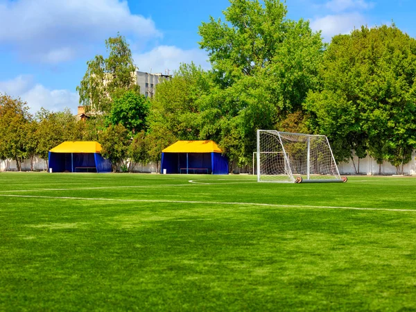 Groene gazon van een voetbalveld met hekken en tenten voor teamspelers. — Stockfoto