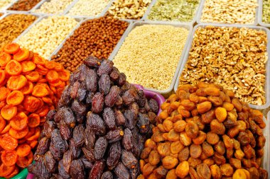 Tarihler, kurutulmuş kayısılar çeşitli fındıkların, bademlerin, fındıkların, cevizlerin, fındıkların, fındıkların, hareket bulanıklığında kaju fıstıklarının arka planında satılıyor..