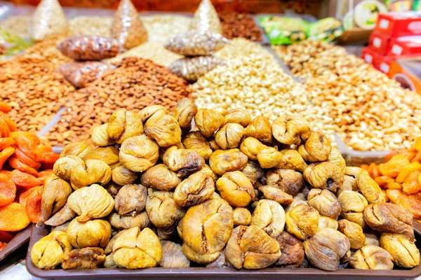 Слайд из уродливого сушеного инжира продается на рынке среди различных орехов в размытом виде . — стоковое фото