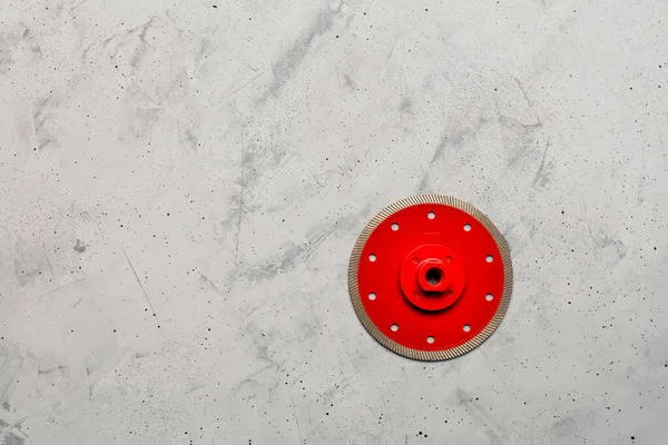 Červená kosočtvercová čepel o průměru 125 mm na šedém betonovém pozadí. — Stock fotografie