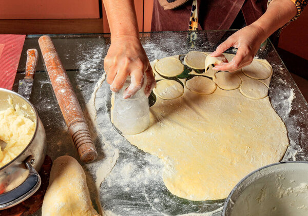 Woman molds Ukrainian dumplings. Ukrainian traditional cuisine.