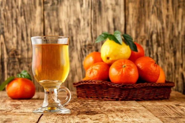 Citrus tea in a glass cup on a background of mandarin and lemon fruits in blur. — Stock Photo, Image