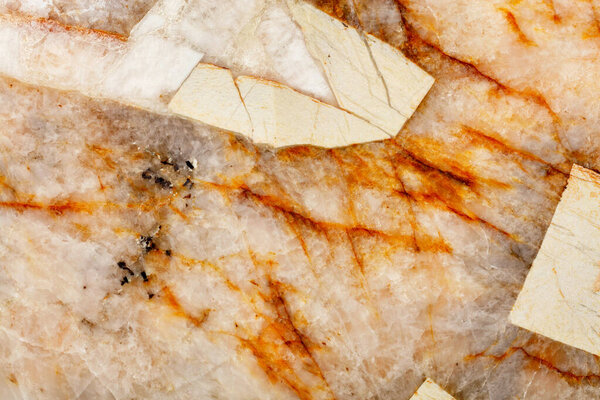 Brown cracks in the heterogeneous structure and surface texture of beige marble, close-up, top view.