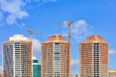 Camdan ve betondan yapılmış modern yüksek binaların simetrik cephelerinin bir parçası, mavi bulutlu gökyüzü, yukarı bakan kule vinçleri, boşluğu kopyalamak,